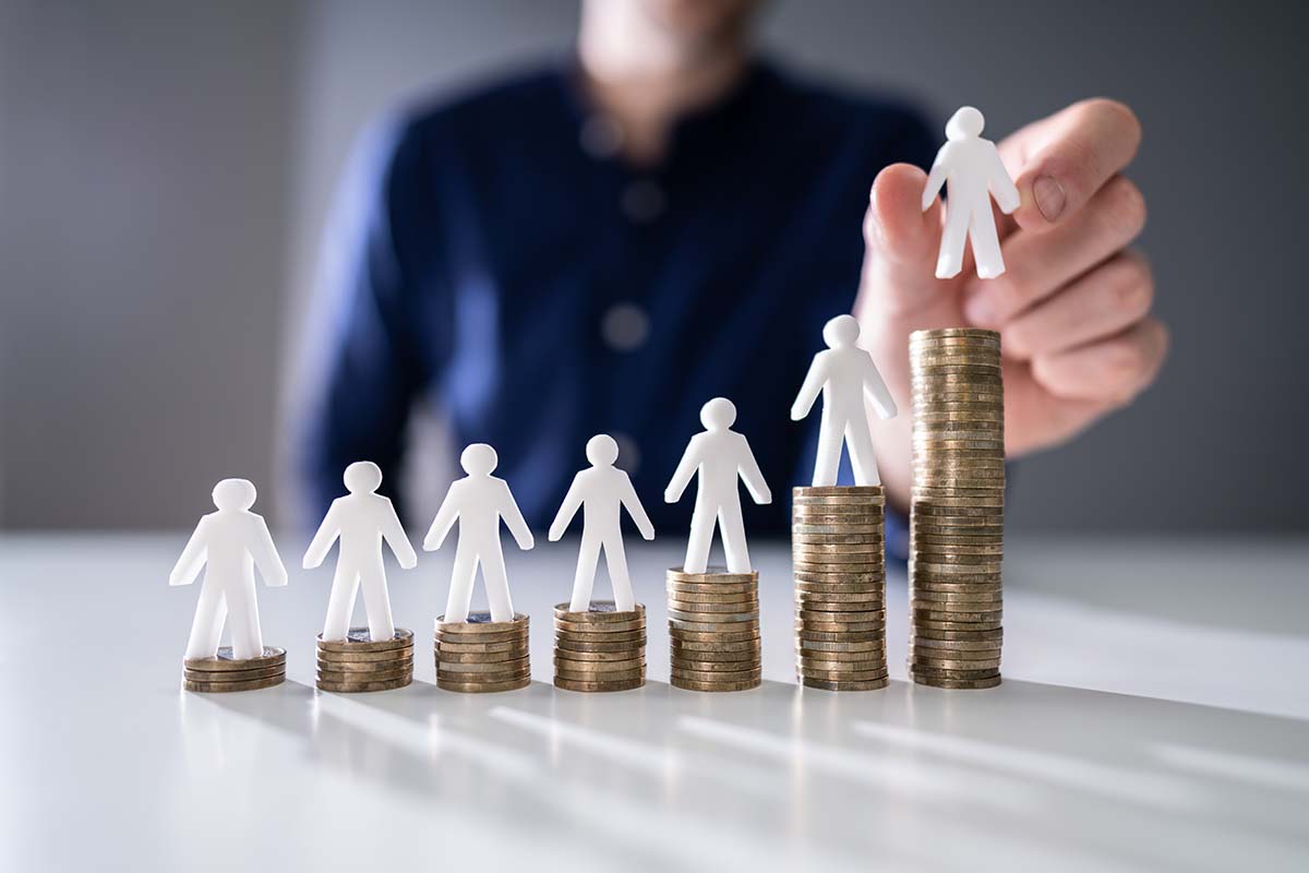 Plastic white stick men standing on increasing tower of coins