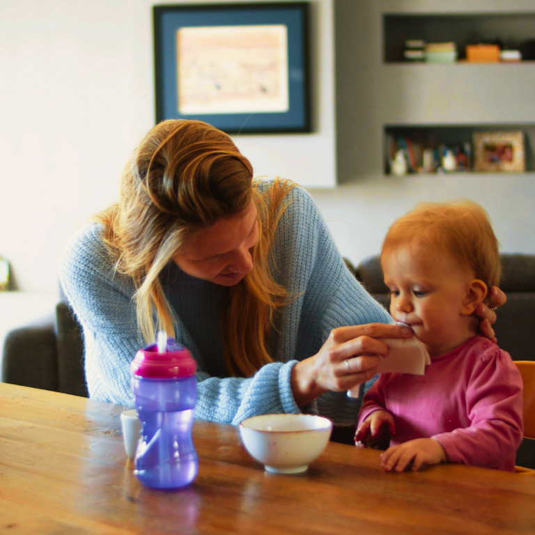 Woman feeding toddler at the table |