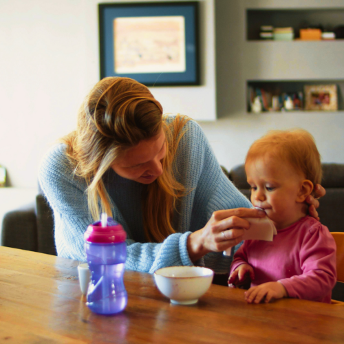 Woman feeding toddler at the table | live in nanny